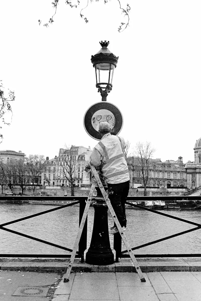 Employee cleaning a street sign in Paris